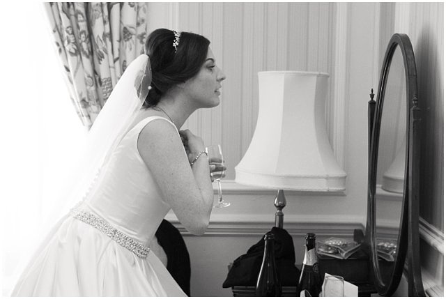 Black and white photo of bride putting on makeup