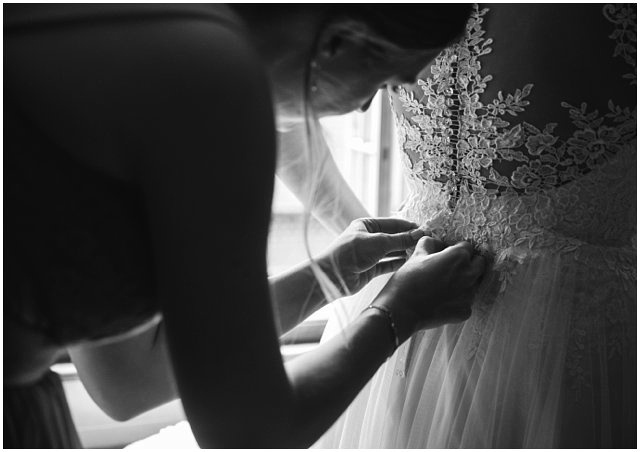 classic black and white photo of bride getting into her wedding dress