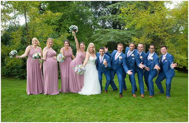 fun bridal party photo with bridesmaids in mauve and groomsmen in blue suits