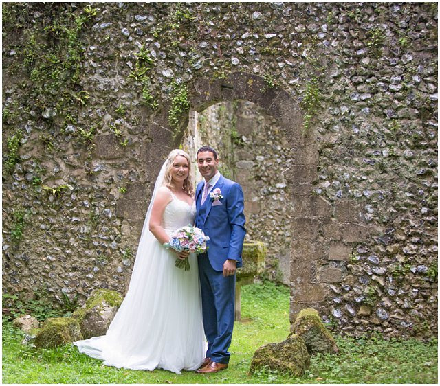 bride and groom posing for photo under arch