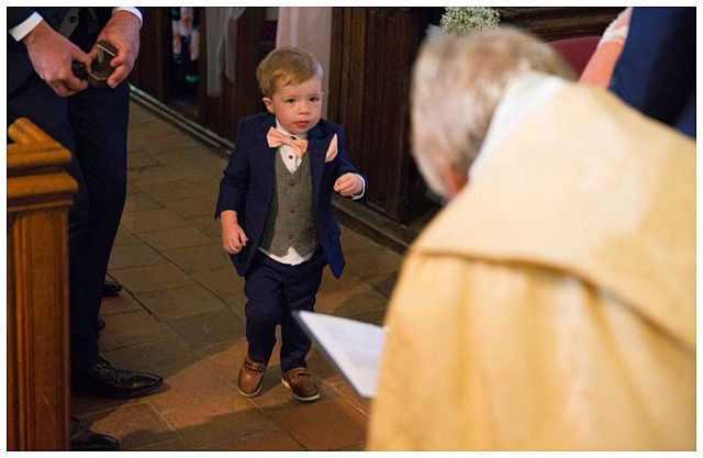 candid photo of ring bearer during wedding ceremony at St. Mary Magdalene Church for Hampden House wedding